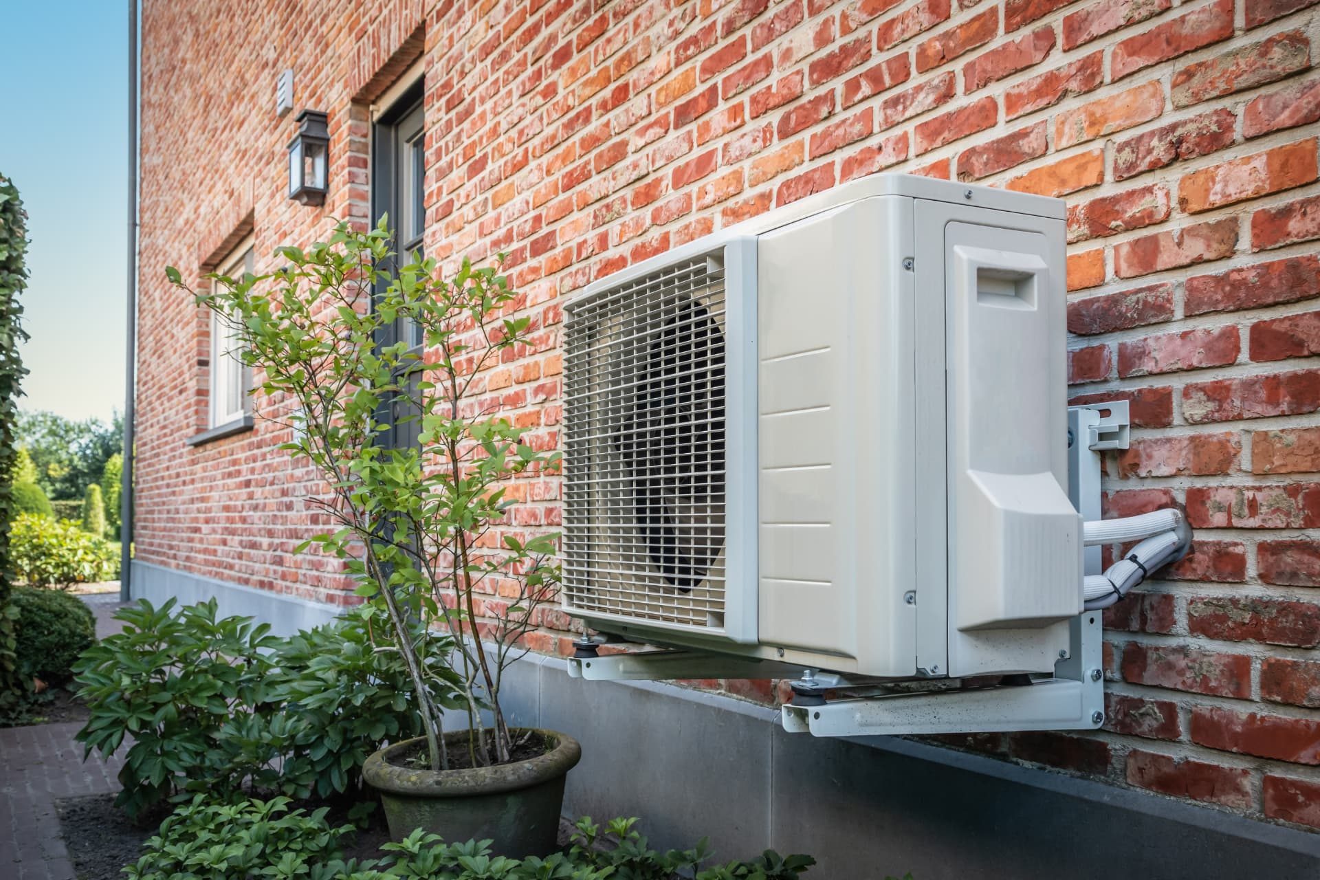 New wall-mounted air conditioning condenser installed on a brick Northeast Ohio home