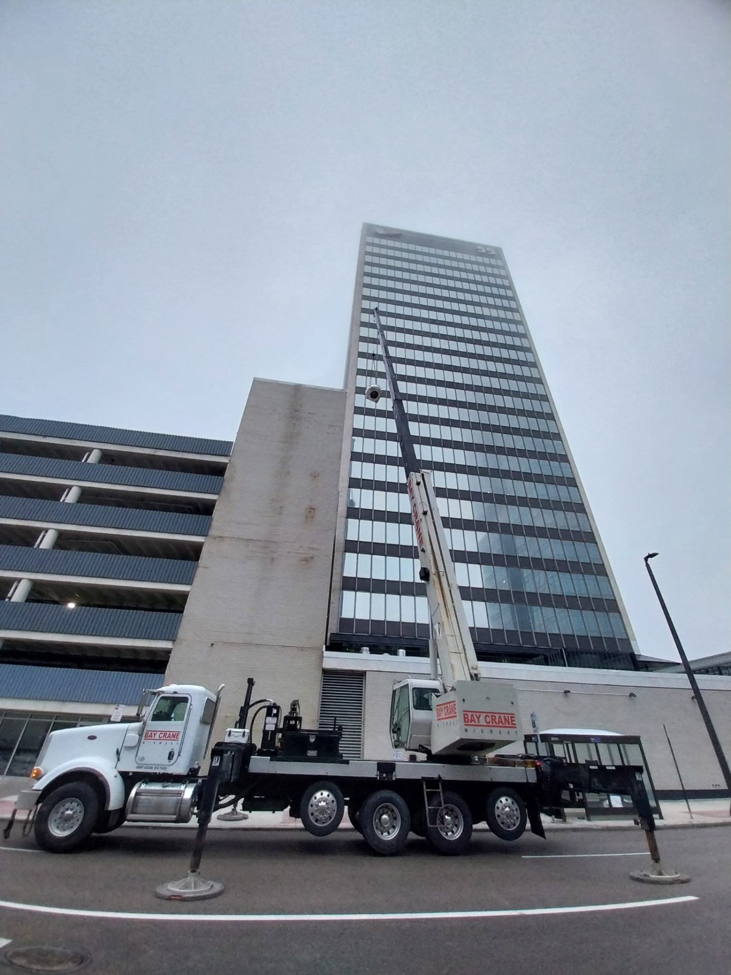 Crane truck staged in downtown Cleveland to hoist rooftop HVAC equipment onto a high-rise office tower for JD Indoor Comfort